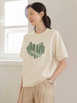 クリームのグリーンハート柄半袖Tシャツ 着用 手をポケットに