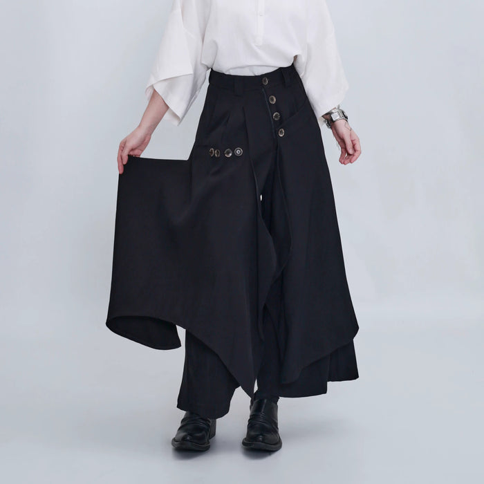 ブラックのアシンメトリースカートパンツ 着用 外側の布をつまんで