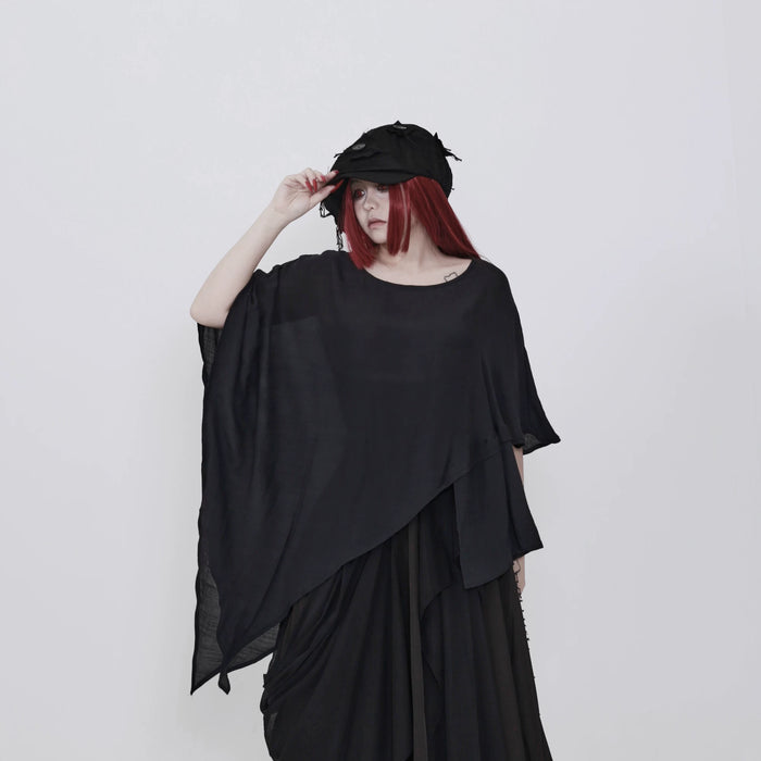黒のアシンメトリートップス 着用 帽子に手を添えた着こなし