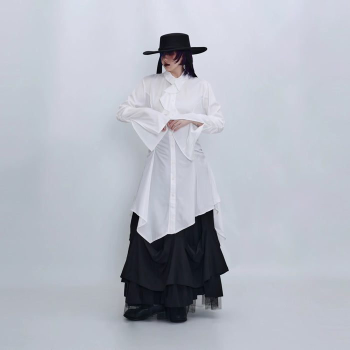 ホワイトのロングシャツ 着用 帽子を押さえたポーズ