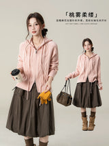 ピンクのフード付きケーブルニットカーディガン 着用 カップを持ったポーズ