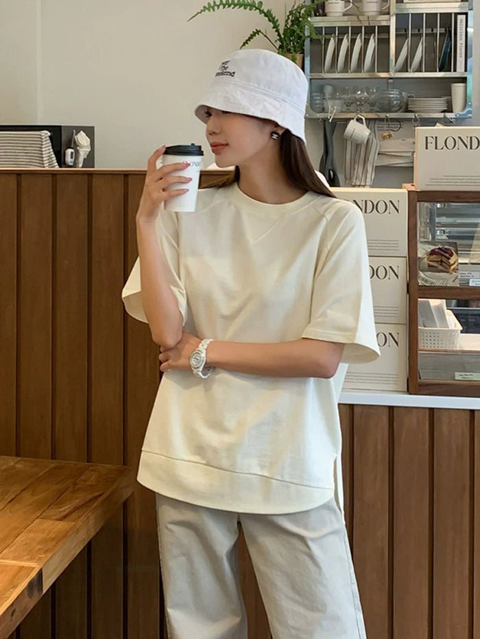 クリームのAラインTシャツ 着用 バケットハットでコーヒーを手に