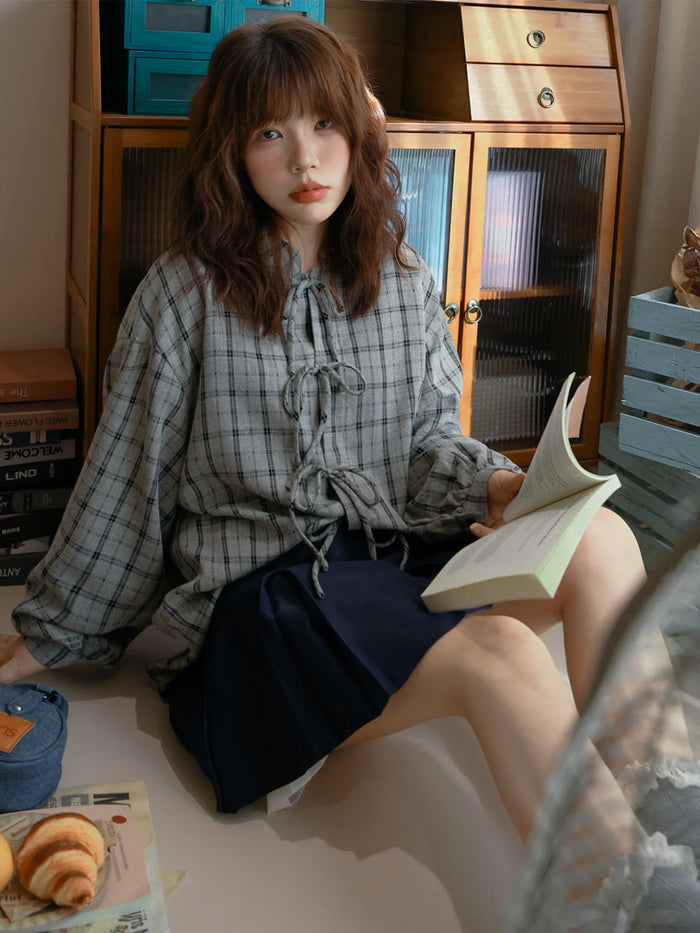 グレーのチェックシャツ 着用 本を持って
