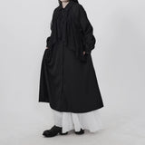 ブラックのフリルワンピース 着用 斜め 手をポケットに添えたポーズ