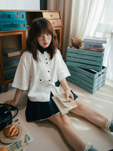 ホワイトの半袖シャツ 着用 本を持って