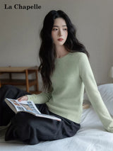 ライトグリーンのクルーネックニット 着用 雑誌を持ったポーズ