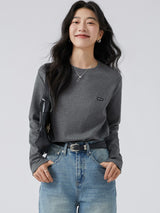 ダークグレーのワッペン付き 長袖Tシャツ 着用 バッグを持ったポーズ