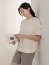 クリームのコットンTシャツ 着用 本を持って