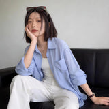 ライトブルーの薄手シャツ 着用 ソファで頬杖をついて