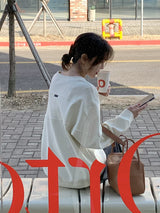 アイボリーホワイトの長袖Tシャツ 着用 ベンチに座って