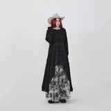 ブラックのアシンメトリーワンピース 着用 帽子に手を添えた着こなし