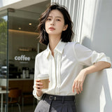 ホワイトのシフォン調シャツ 着用 コーヒーを持って