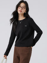 ブラックのワッペン付き 長袖Tシャツ 着用 バッグを提げたポーズ